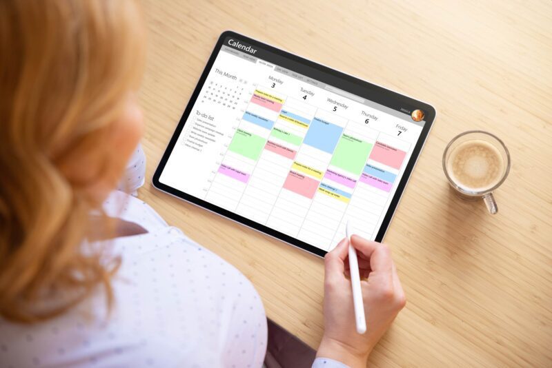 User interacting with a digital planner on iPad using Apple Calendar and stylus for scheduling
